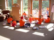 Little kids are sprawled out on the floor of the library, each intently exploring a different book.